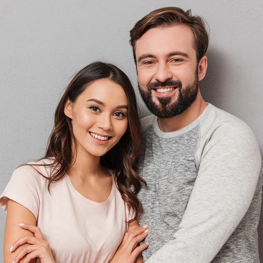 Smiling couple hugging and looking at the camera after dental implants in Berthoud